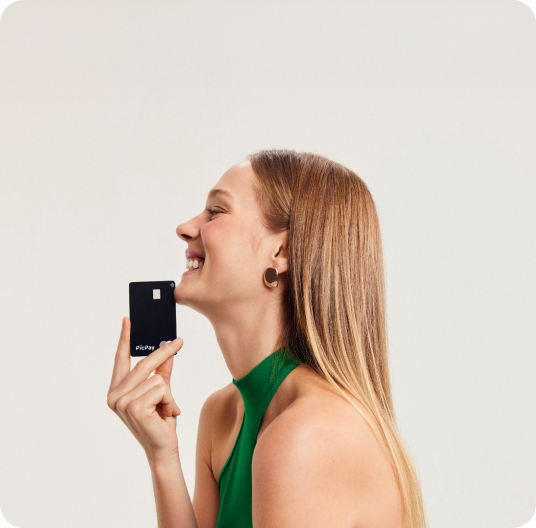 Mulher em um fundo bege com uma camiseta verde segurando um cartão black do PicPay.