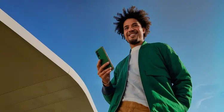 Pessoa em ambiente externo segurando um smartphone.