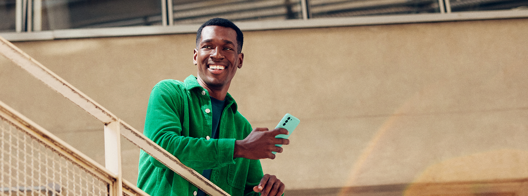 Homem sorridente na escada segurando um celular